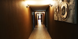 Un pasillo con paredes de madera y suelo de baldosas, que conduce a una puerta al final.