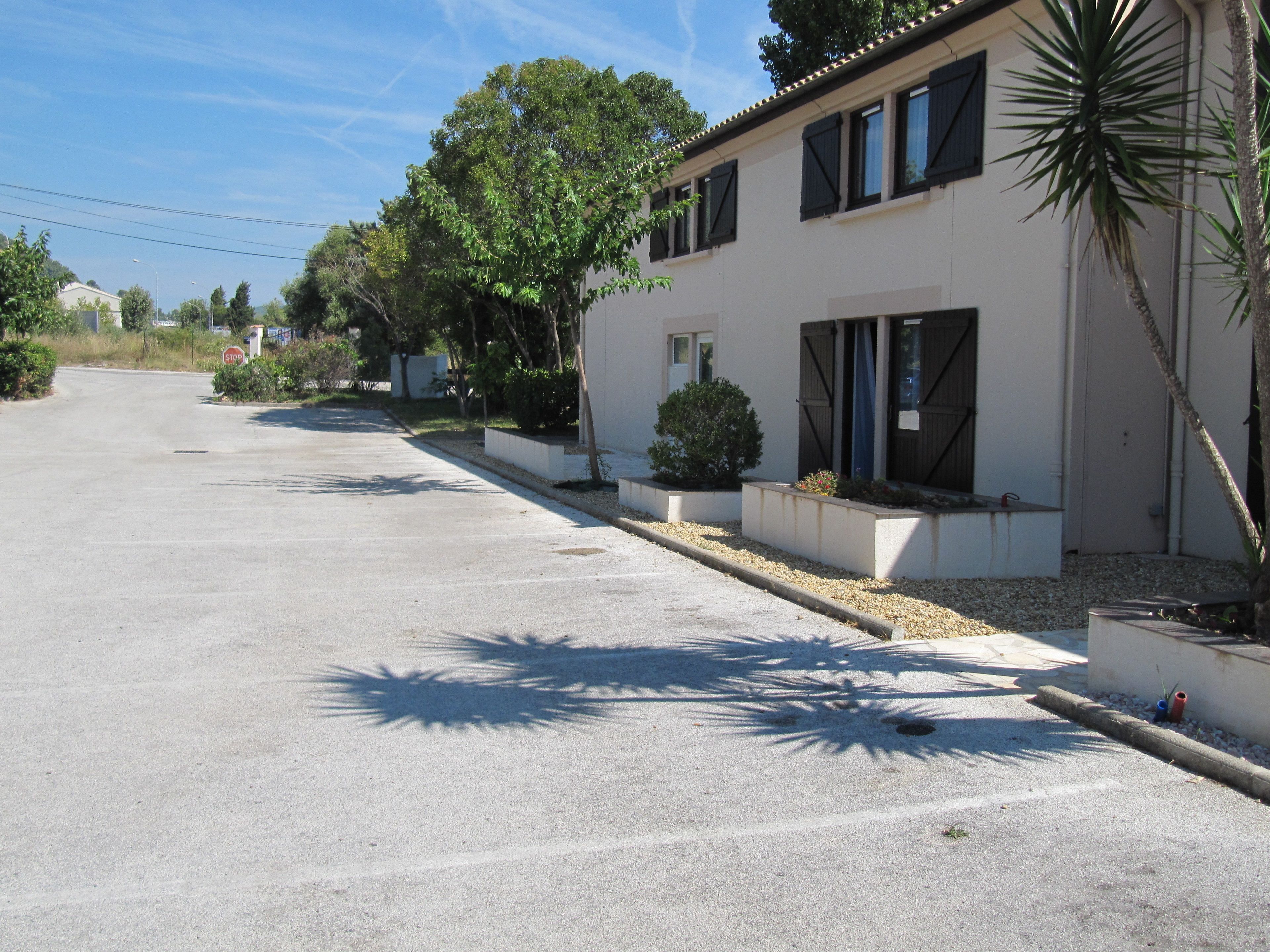 A quiet street with a white building featuring large windows and a covered porch.