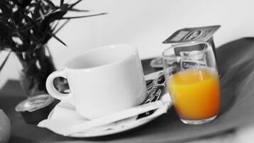Una taza y platillo blancos con un vaso de jugo de naranja sobre una bandeja.