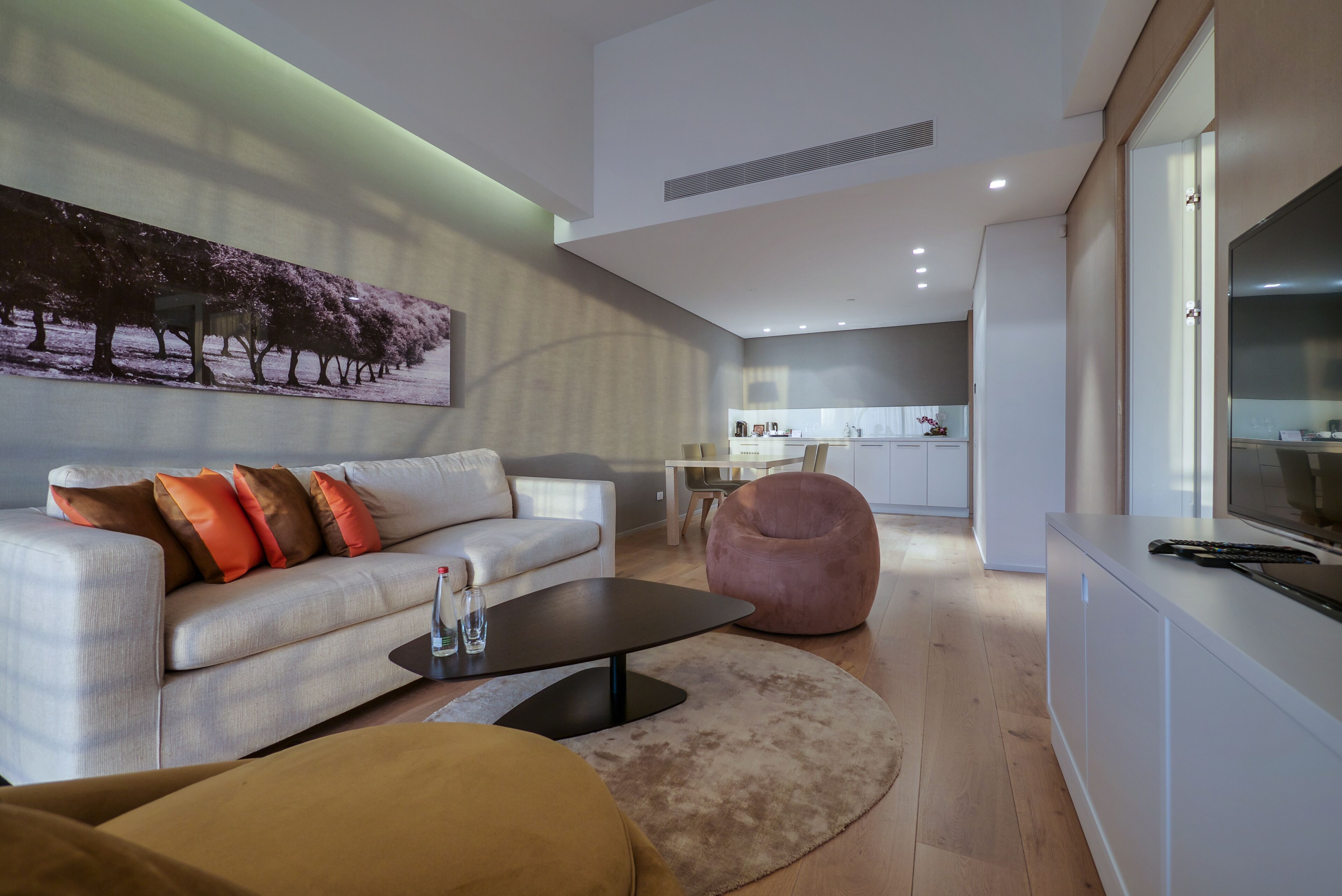 A modern living room with a sofa, coffee table, and a large painting of trees.
