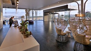Eine großzügige Lobby mit Empfangsschalter, Sitzgelegenheiten und großen Fenstern mit Blick auf die Landschaft.