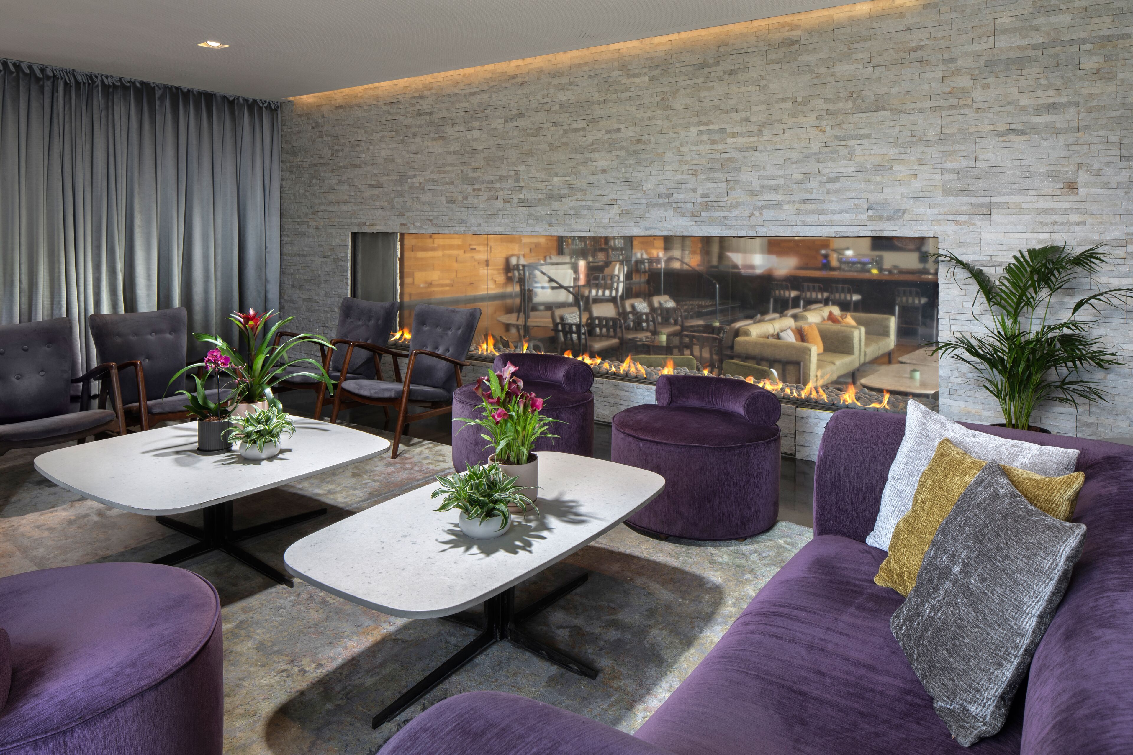 A modern living room with a fireplace, comfortable seating, and a large TV screen.