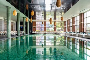 Una piscina techada, una piscina al aire libre, sombrillas