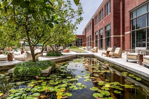 A courtyard with a pond, seating areas, and a building with large windows. - Cramim by Isrotel exclusive (Mateh Yehuda)
