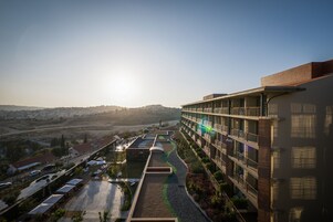 Un hotel moderno con varios pisos, zonas de estar al aire libre y vistas del paisaje circundante.