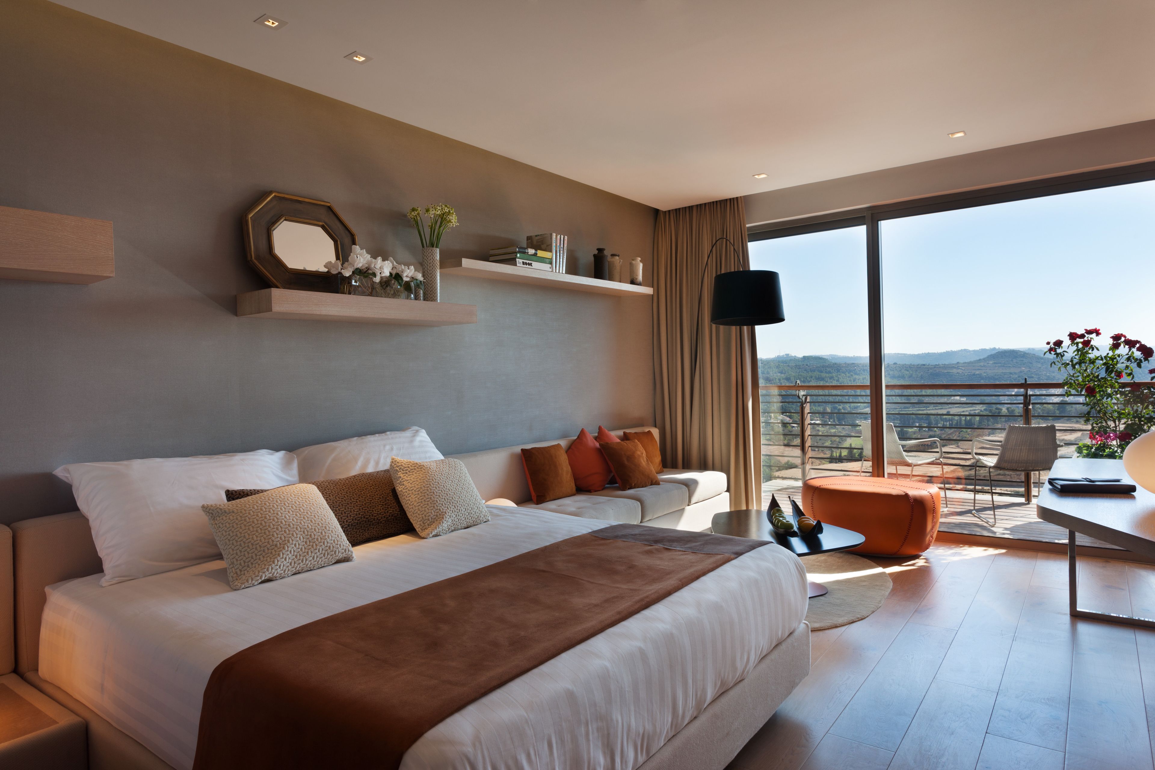 Une chambre d’hôtel moderne dotée d’un grand lit, d’un balcon avec vue et d’un coin salon avec une table.
