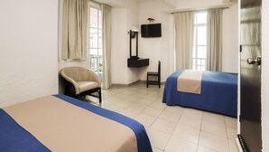 A hotel room with two beds, a chair, a desk, a television, and a window with curtains. - Hotel Trianon (Veracruz)