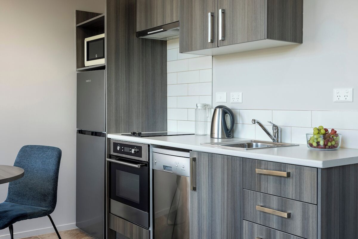 Una cucina moderna con mobili grigi, elettrodomestici in acciaio inossidabile e un piano di lavoro bianco.