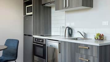Una cucina moderna con mobili grigi, elettrodomestici in acciaio inossidabile e un piano di lavoro bianco.