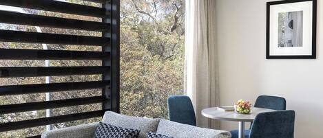 A modern room with a sofa, two chairs, a small table, and a window with a view of trees.