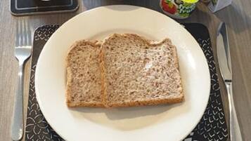 A breakfast setting with toast, marmite, orange juice, and milk cartons on a table.