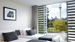 A hotel room with two beds, a large window with a city view, and a framed picture on the wall. - Quest on Beaumont (Auckland)