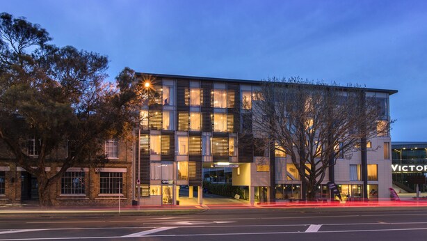 A modern hotel with a glass facade, multiple floors, and a prominent entrance. - Quest on Beaumont (Auckland)