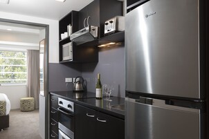 A modern kitchen with a built-in oven, a stainless steel refrigerator, and a wine bottle on the counter.