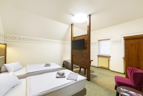 A hotel room with two beds, a wooden wardrobe, a small table, and a chair. - Hotel U Šimla (Karlovy Vary)