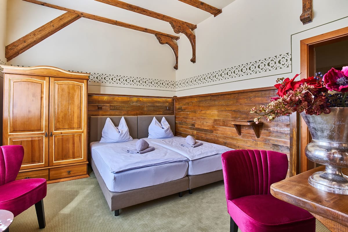 A bedroom with a double bed, wooden wardrobe, and a large vase with flowers.