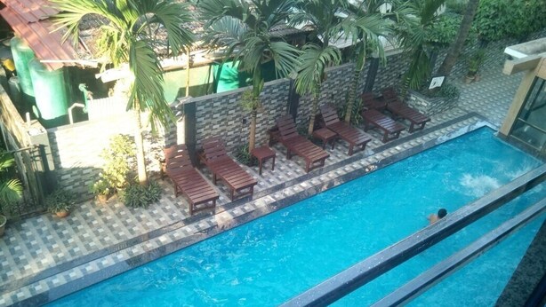 Una piscina con sillones de descanso y palmeras.