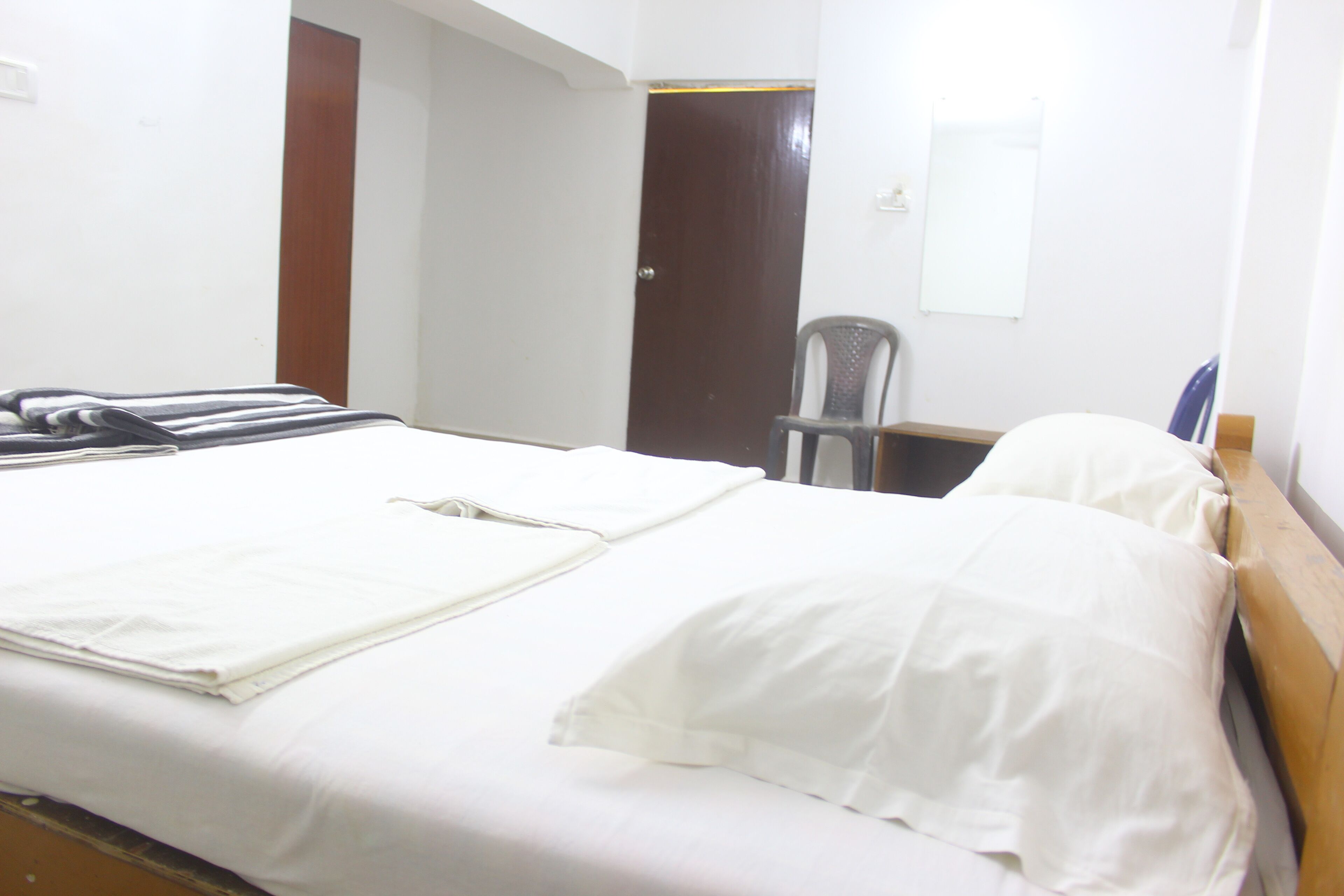 Una habitación de hotel con una cama, una silla, un escritorio y una puerta.