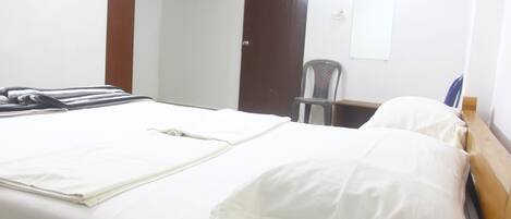 Una habitación de hotel con una cama, una silla, un escritorio y una puerta.