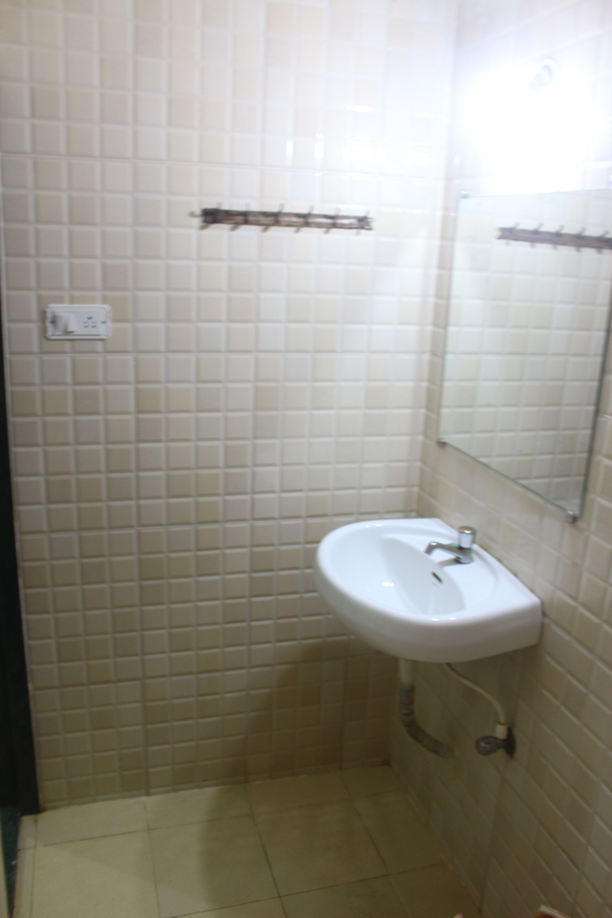 A bathroom with white tiles, a sink, and a mirror.