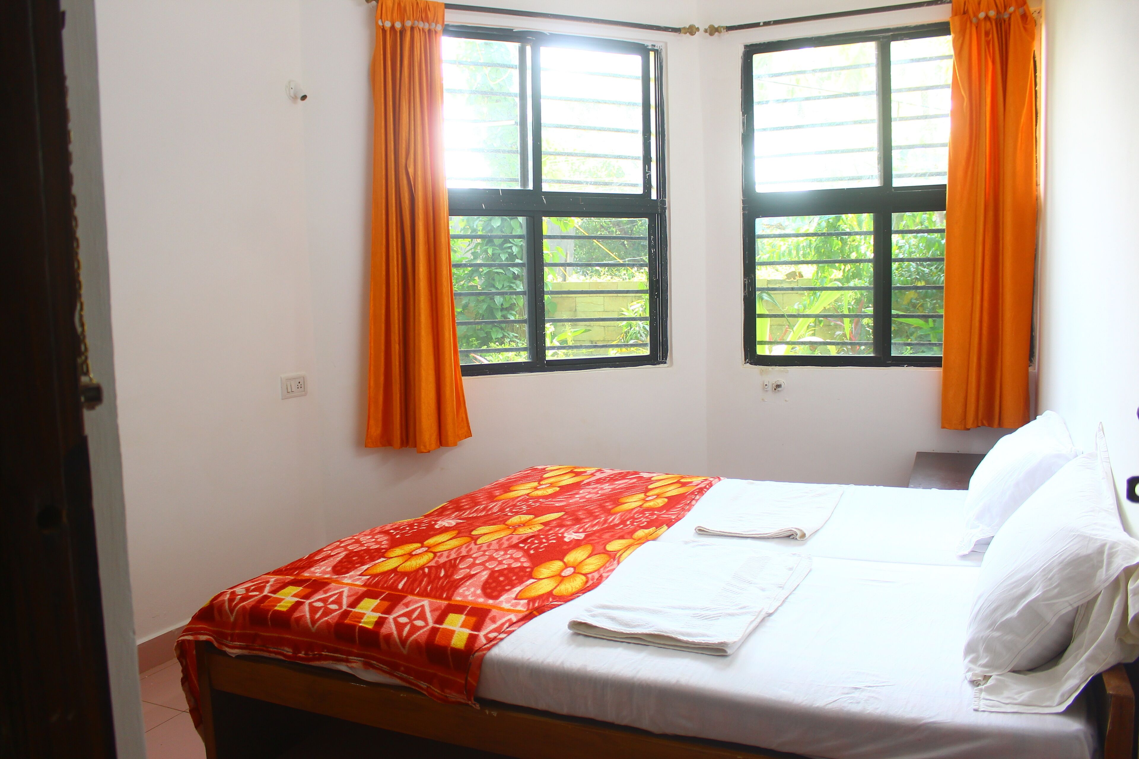 A room with two beds, each with white linens and orange curtains.