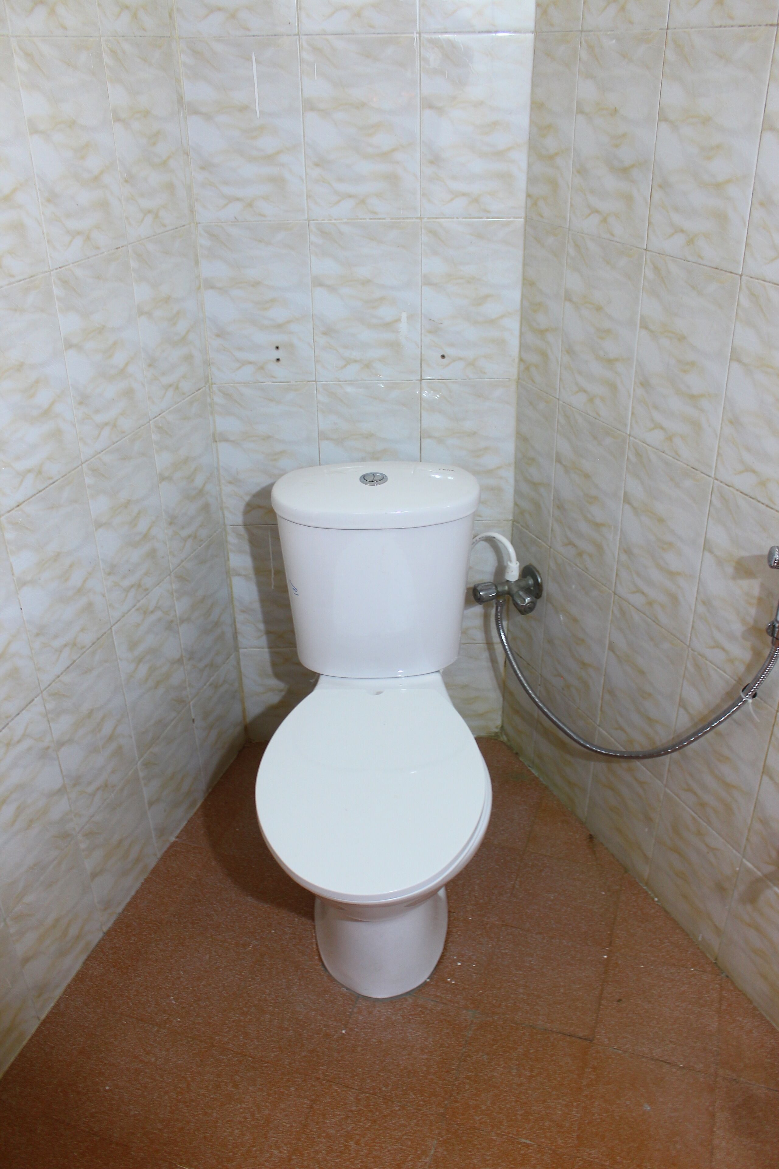 Une salle de bain avec des toilettes, une douche et des murs carrelés.