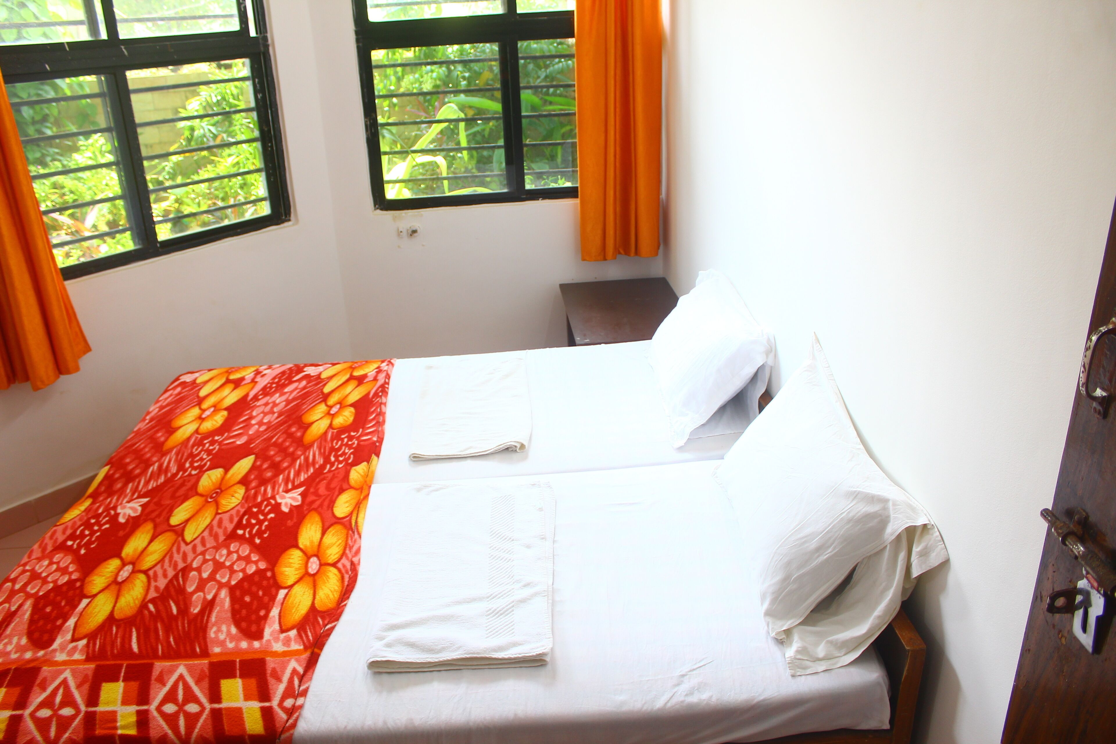 A neatly made bed with a red and white bedspread, white pillows, and a wooden headboard.