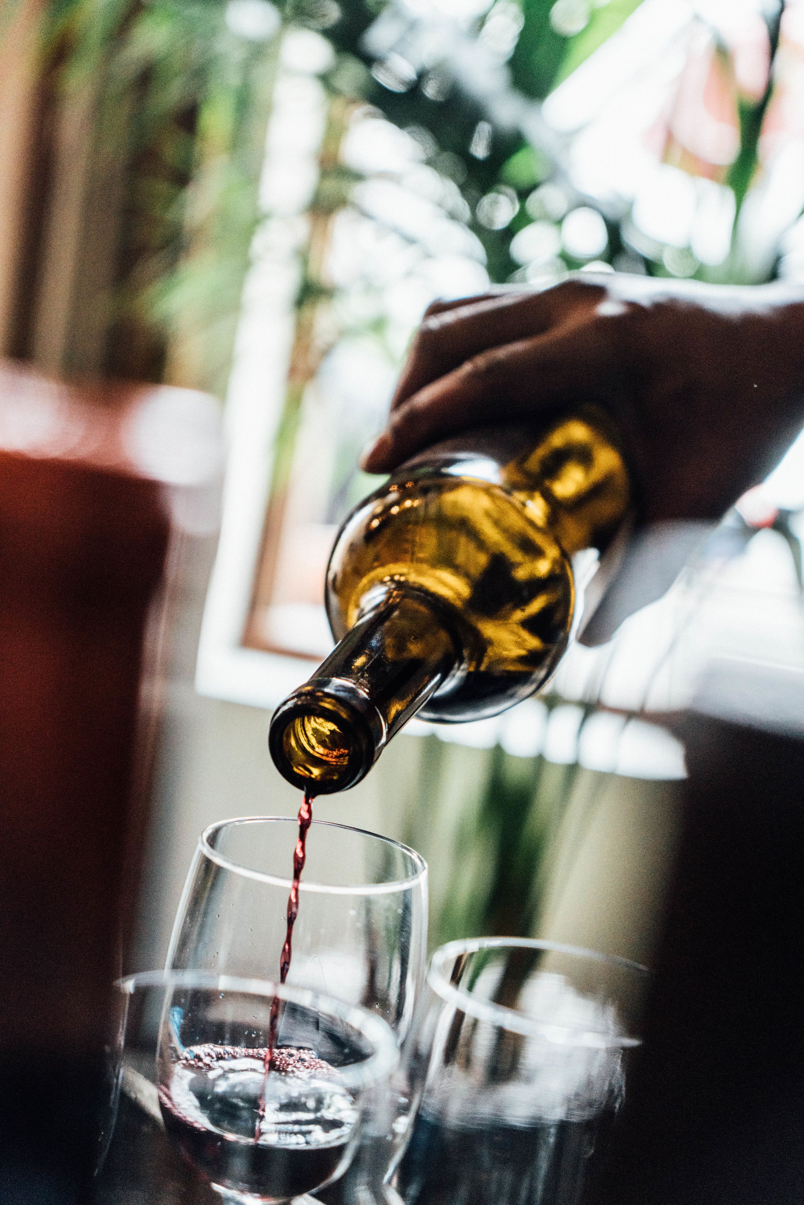 Eine Hand gießt Flüssigkeit aus einer Flasche in ein Glas.