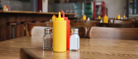 A table with condiments and salt shakers in a restaurant setting.