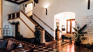 Un sol à carreaux, un canapé en cuir, un escalier et un mur avec du texte.