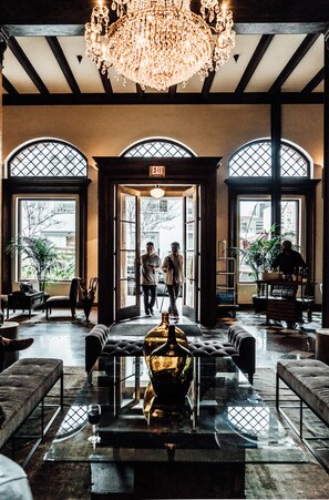 A lobby with a chandelier, large windows, and a bar area. - Hotel Normandie (Los Angeles)