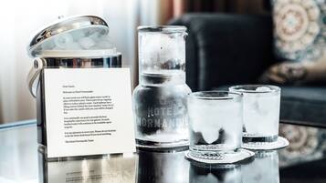 A glass water carafe, a glass jar, and three glasses on a table with a message card.