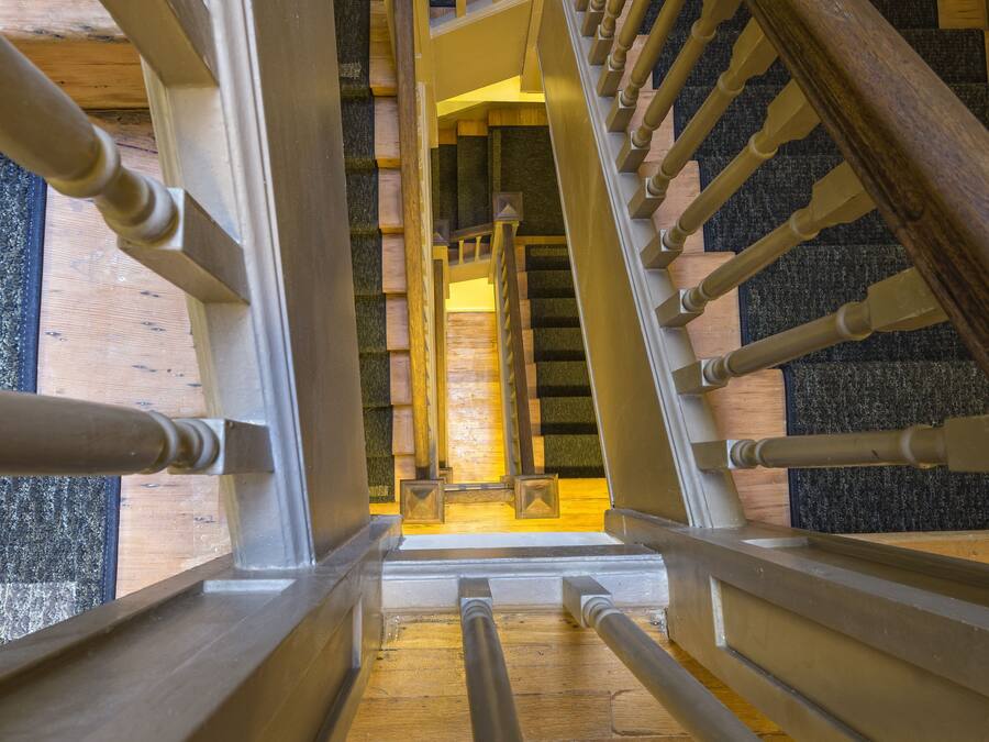 A staircase with wooden railings and a wooden floor leading to an upper level.