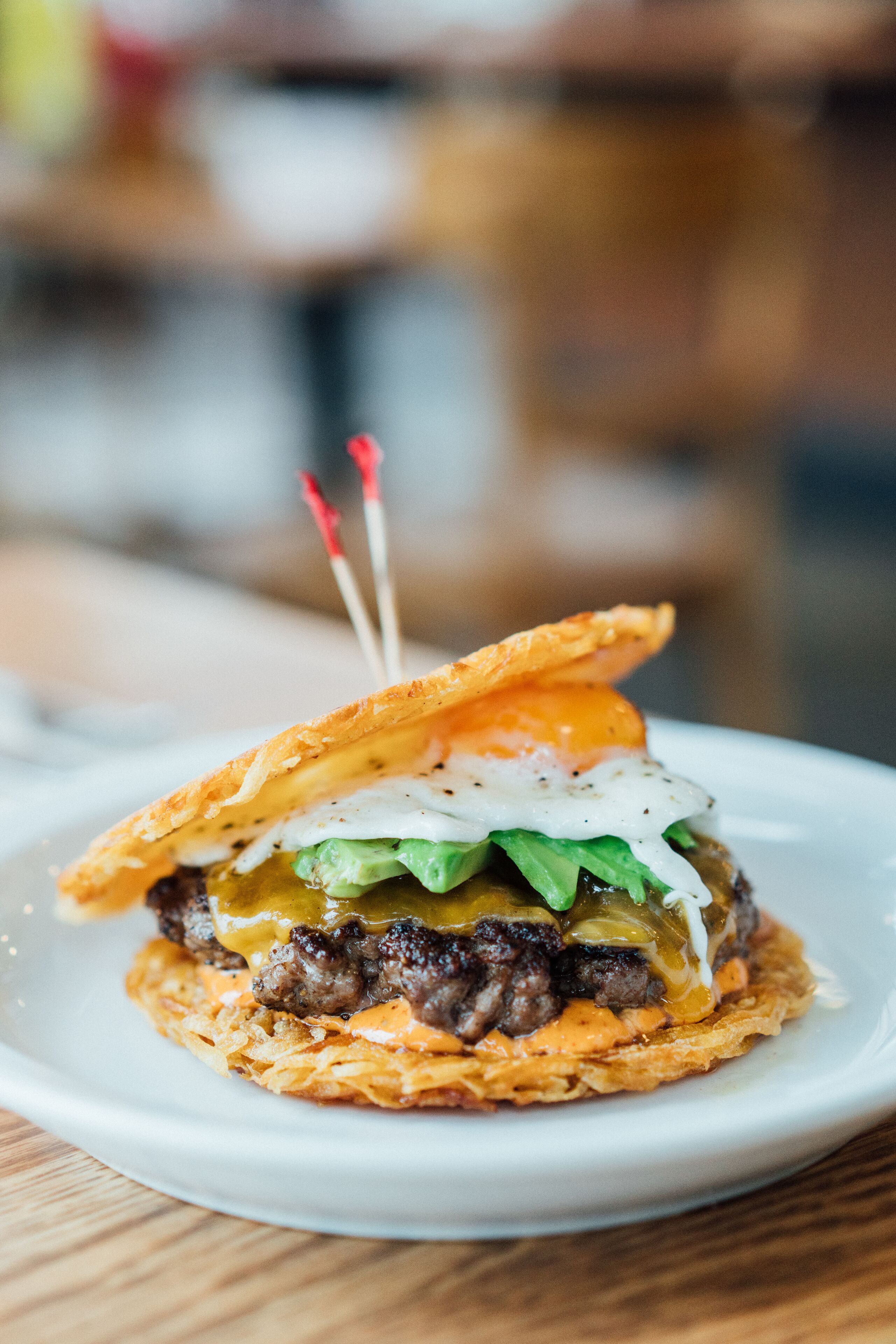 Une assiette avec un hamburger, des cornichons et une sauce.