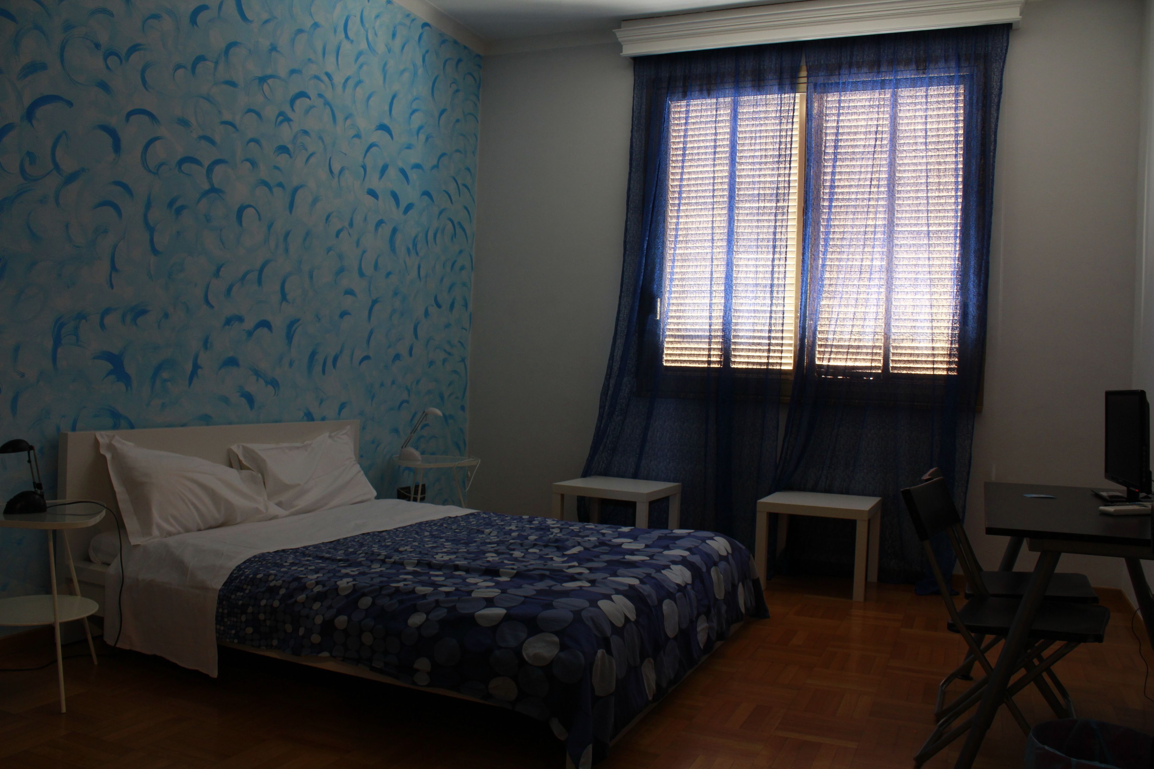 Un dormitorio con cama, escritorio y silla.