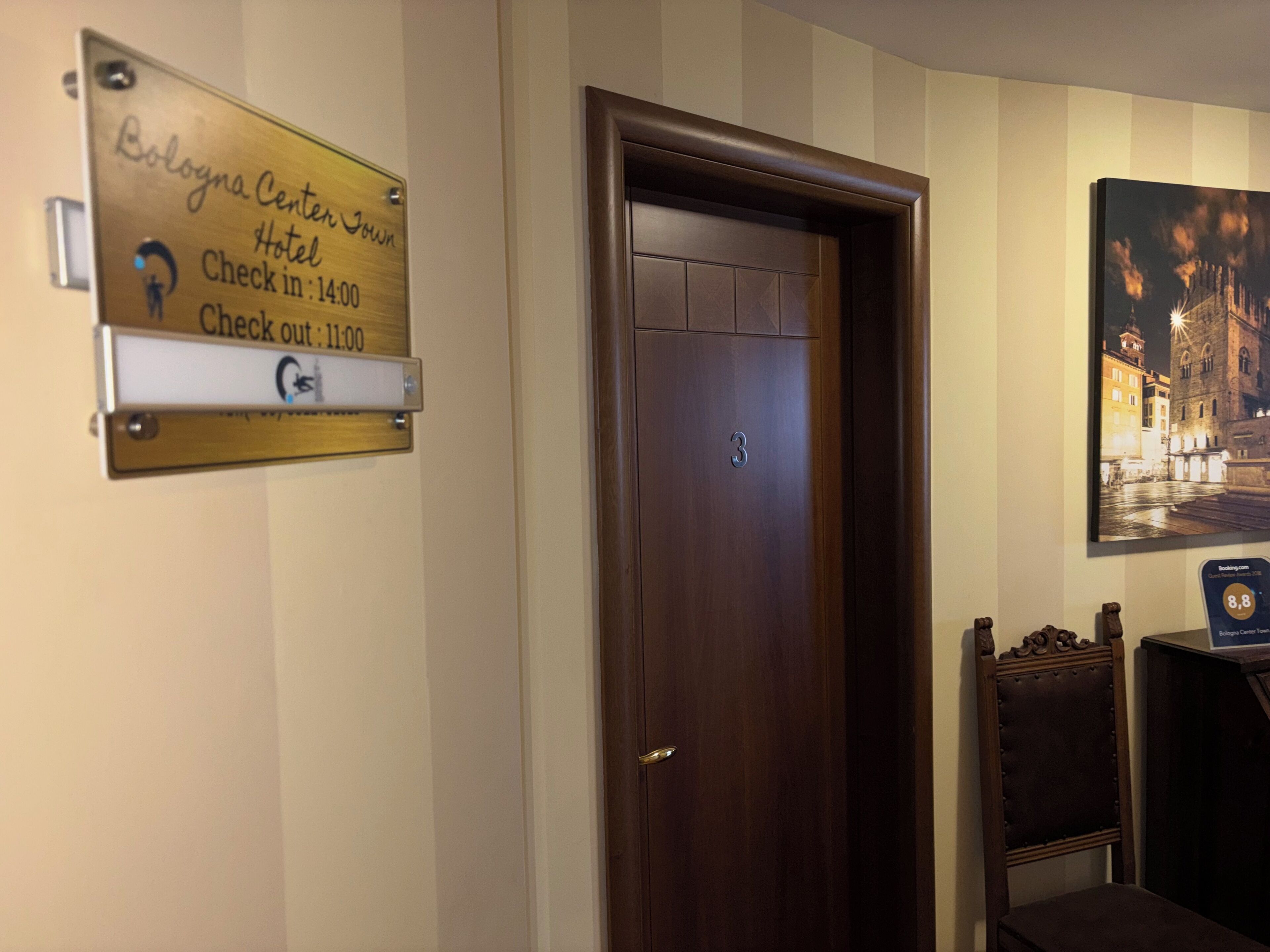 Habitación de hotel con puerta de madera, un cartel de registro de entrada/salida y un cuadro en la pared.