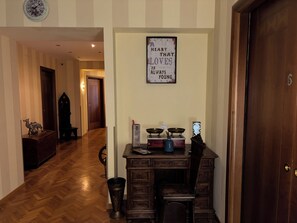 A hallway with a wooden floor, a desk with a vase, a sign on the wall, and a door marked with the number 6. - Bologna Center Town (Bologna)