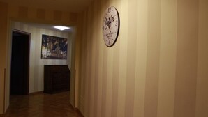A hallway with a clock on the wall, a door at the end, and a poster on the wall. - Bologna Center Town (Bologna)