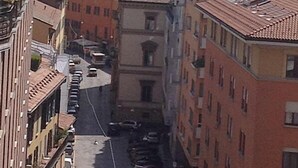 A narrow street flanked by multi-story buildings with uniform architecture, a clear sky, and parked cars. - Bologna Center Town (Bologna)