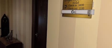 A wooden door with a brass plaque indicating the Bologna Center Town Hotel's check-in and check-out times.