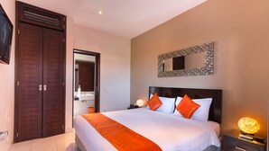 Habitación de hotel con una cama grande, una mesita de noche con lámpara, un armario y un espejo en la pared.