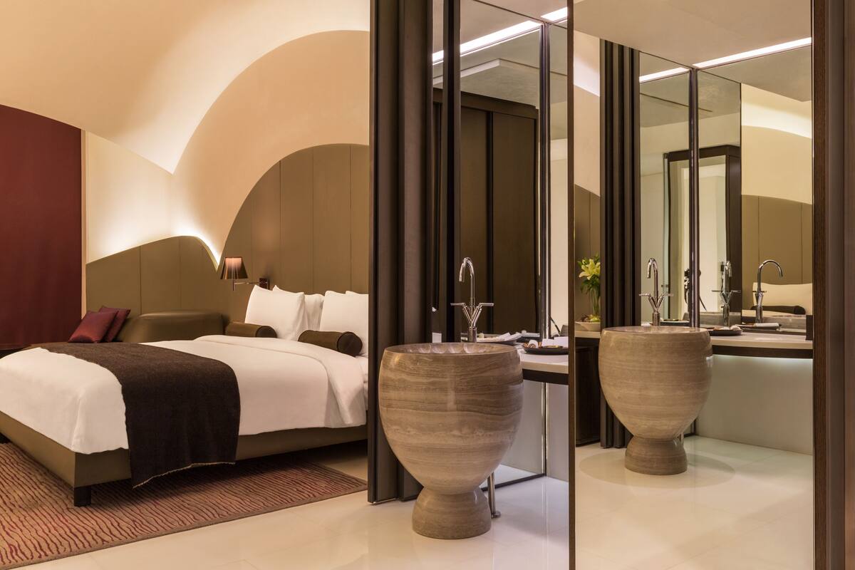 Ein modernes Hotelzimmer mit einem großen Bett, einem Schminktisch mit Spiegel und zwei großen Vasen.