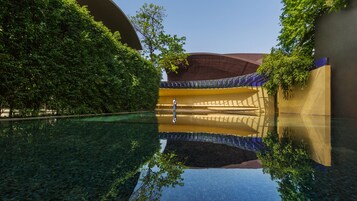 A serene indoor pool with clear water reflecting the architecture, surrounded by lush greenery and a modern design.