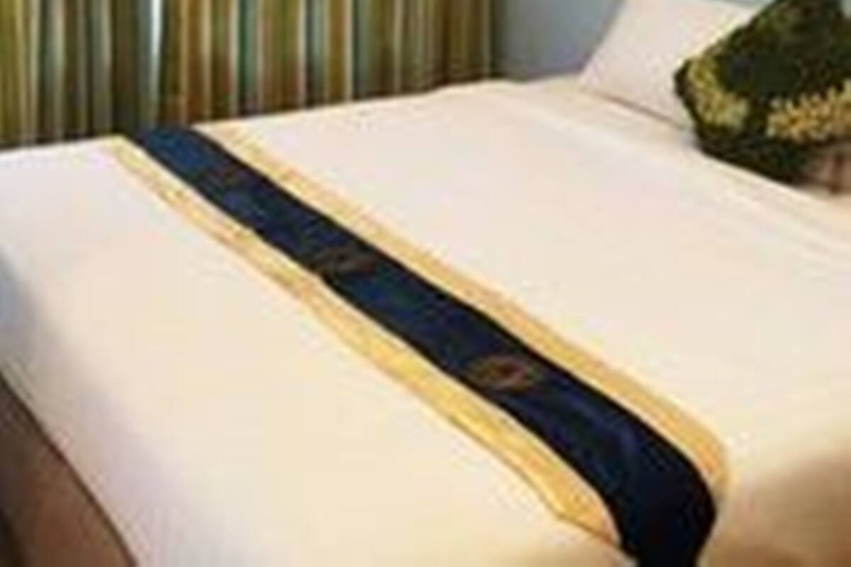 Quarto de hotel com uma cama, cortina listrada e um travesseiro.