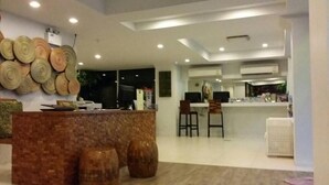 A modern hotel lobby with a reception desk, seating area, and a large window. - Nantra Chaweng Beach, Samui (Koh Samui)