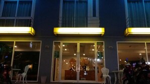 A building with large glass doors and windows, a balcony with yellow lighting, and outdoor seating. - Nantra Chaweng Beach, Samui (Koh Samui)