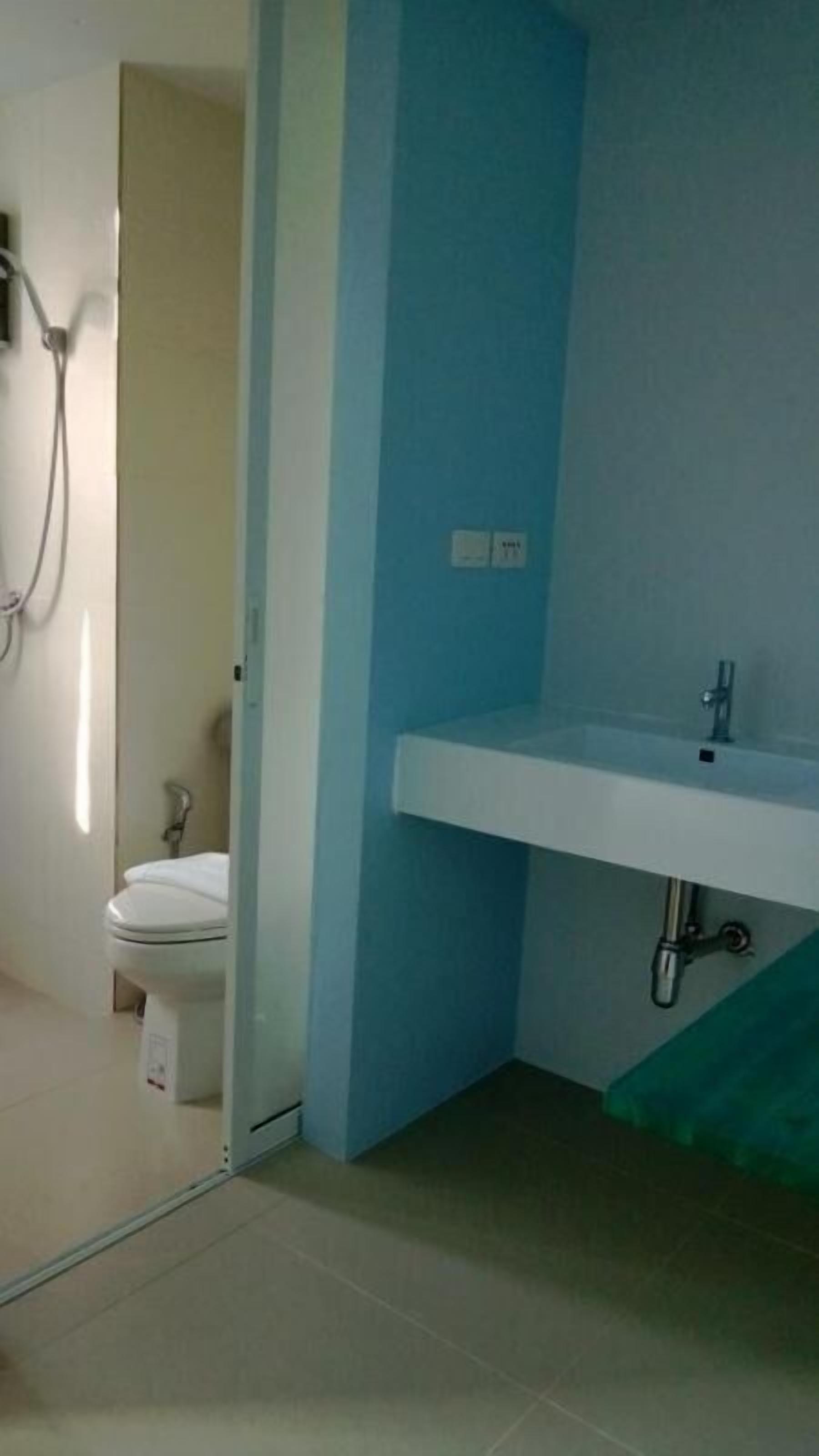 A bathroom with a white sink, a toilet, and a shower area.