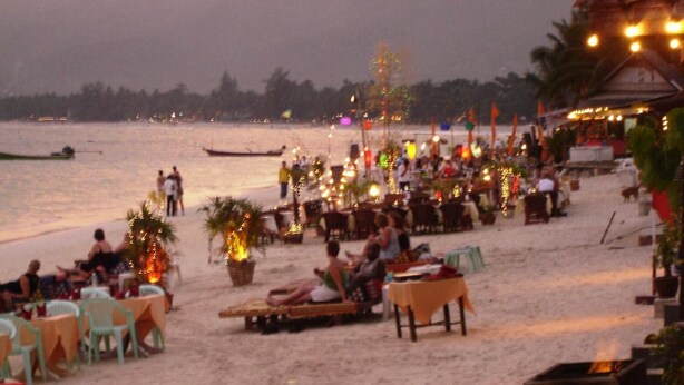 A beachside restaurant with outdoor seating, tables, and chairs, overlooking a body of water with boats. - Nantra Chaweng Beach, Samui (Koh Samui)