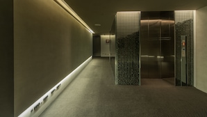 A modern elevator with a metallic finish and a glass panel. - Simple Plus Hotel (Taipei)