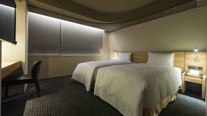 A hotel room with two beds, a desk, a chair, and a nightstand with a lamp. - Simple Plus Hotel (Taipei)